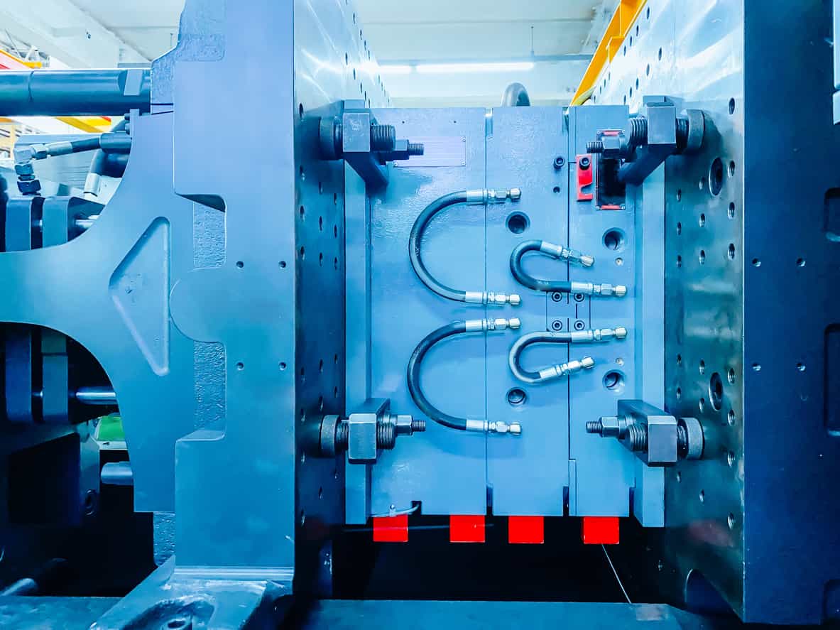 塑膠射出工廠注塑機搭載的金屬模具特寫，展示冷卻迴路與模穴細節
